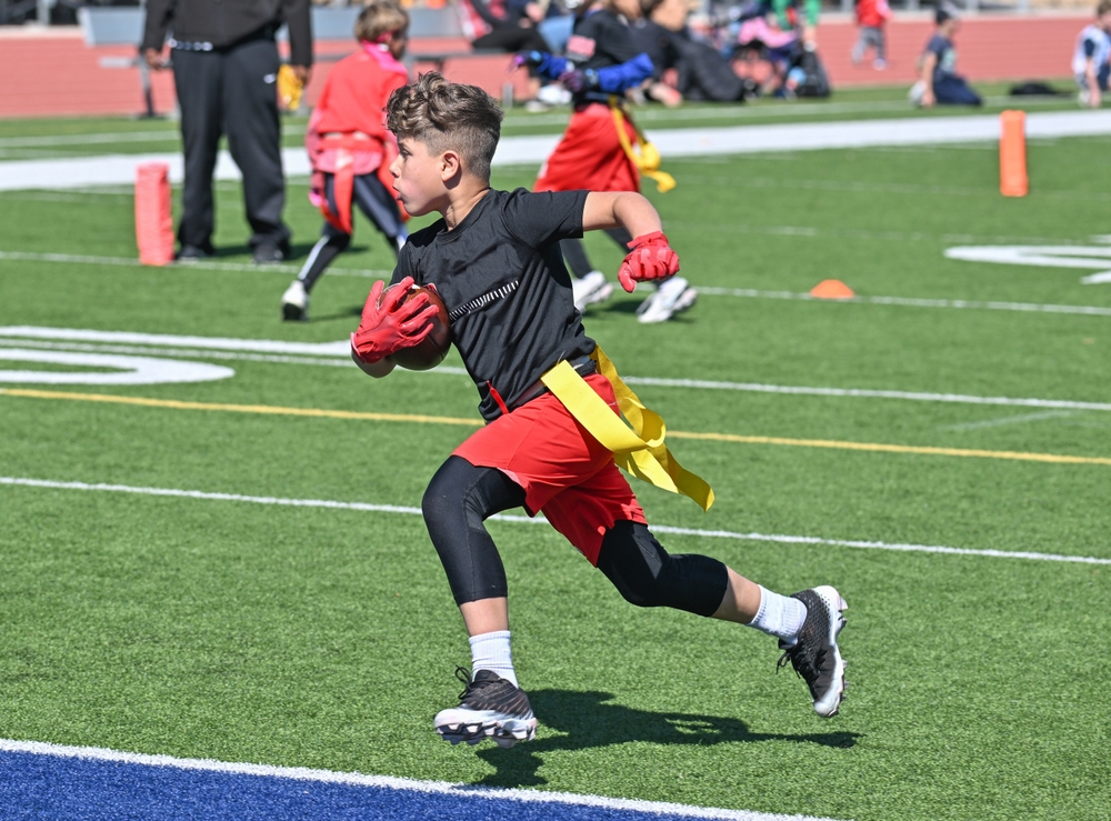 Young boy playing flag football runs into the end zone on a field